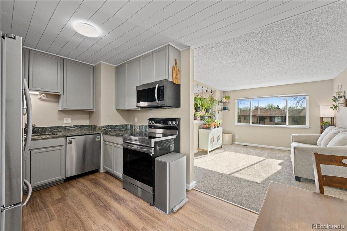 205 Walnut Street Frederick, CO 80530 - Photo 9 of 31 a kitchen with stainless steel appliances granite countertop a stove top oven a sink dishwasher a dining table and chairs with wooden floor