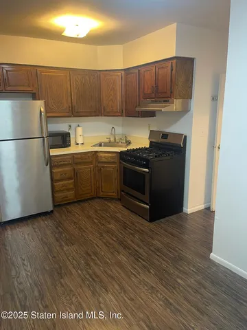 a kitchen with stainless steel appliances granite countertop a refrigerator a stove a sink and a microwave with wooden floor