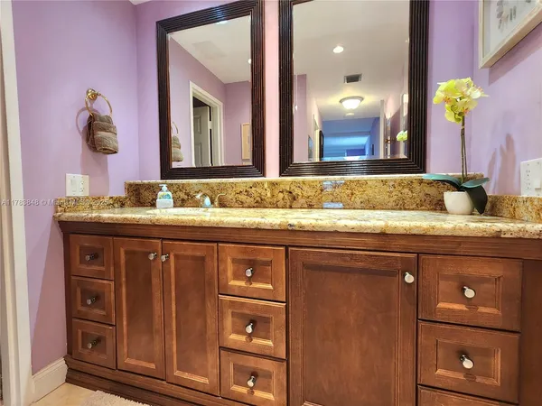 a bathroom with a granite countertop sink a large mirror and a window