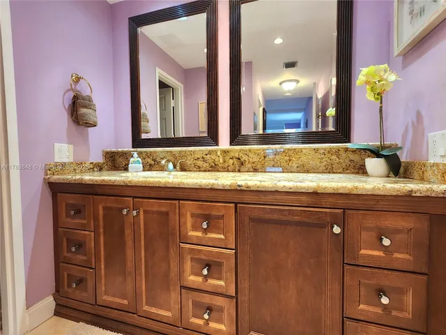 a bathroom with a granite countertop sink a large mirror and a window