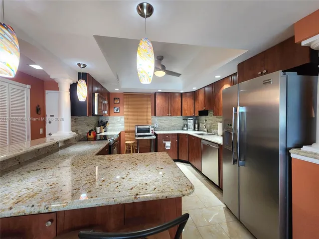 a large kitchen with kitchen island a large counter top stainless steel appliances and cabinets