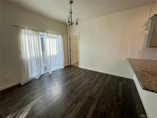 an empty room with wooden floor windows and entrance