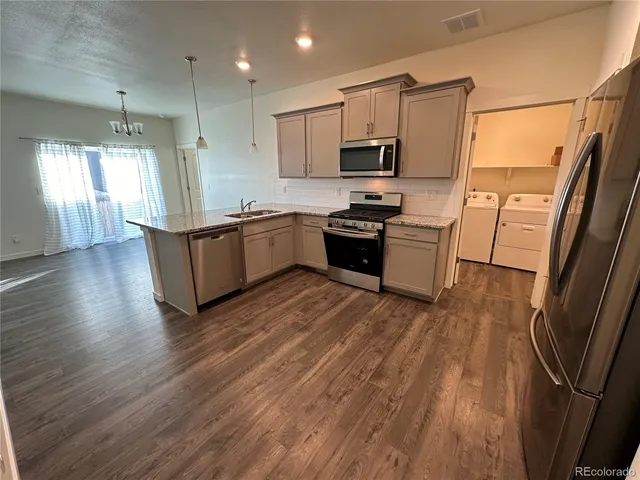 a kitchen with granite countertop a refrigerator a sink dishwasher stove and white countertops with wooden floor