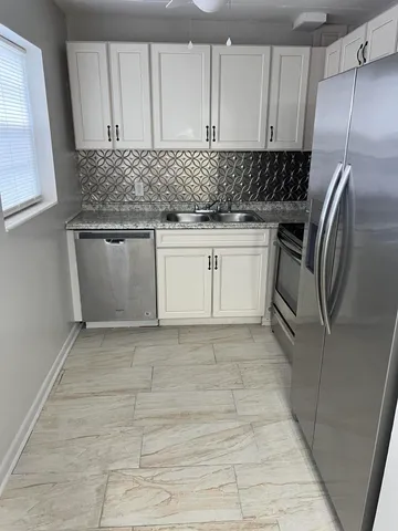 a kitchen with stainless steel appliances granite countertop a refrigerator a stove and a sink