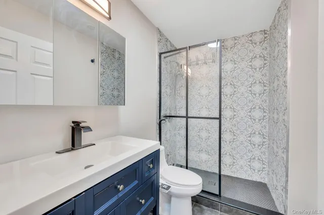 a bathroom with a shower sink vanity mirror and toilet