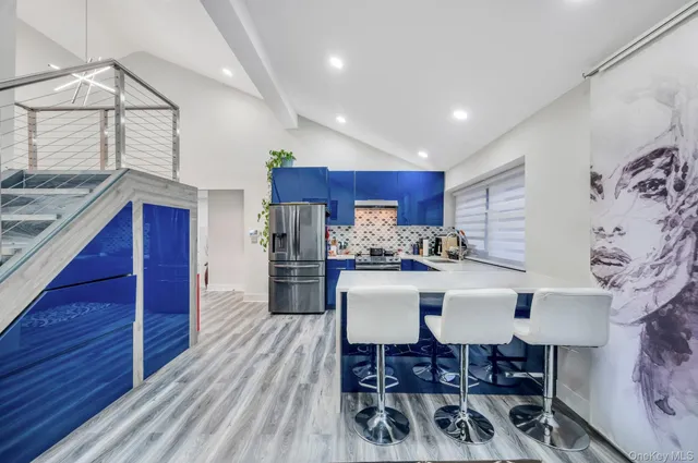 a view of kitchen with stainless steel appliances granite countertop a stove top oven a chimney and a dining table with wooden floor