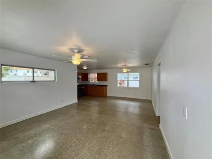 an empty room with windows and chandelier fan