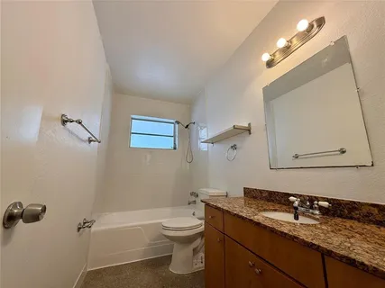 a bathroom with a granite countertop sink a toilet and a mirror