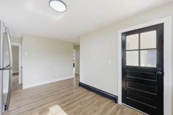 a view of an empty room with wooden floor and a window
