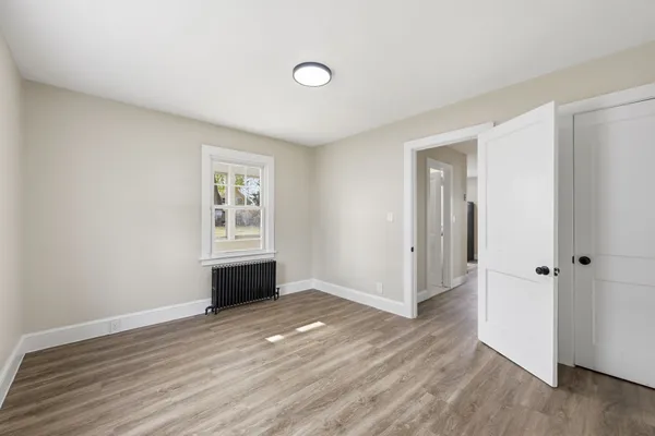 an empty room with wooden floor and window