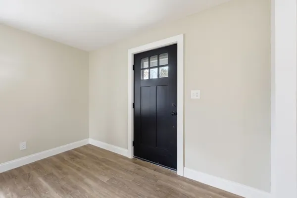 a view of an empty room with wooden floor and closet