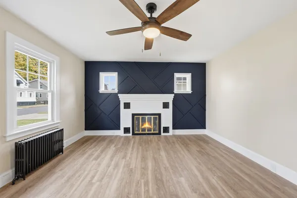 a view of a livingroom with a fireplace a ceiling fan and window