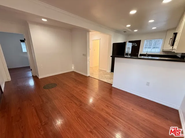 a view of kitchen with stainless steel appliances wooden floors and view living room