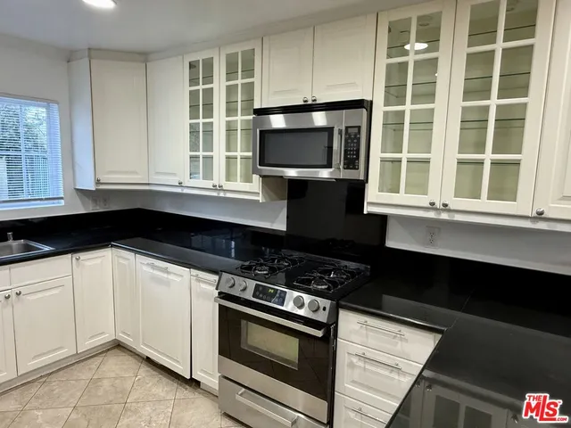 a kitchen with granite countertop a stove a sink and a microwave