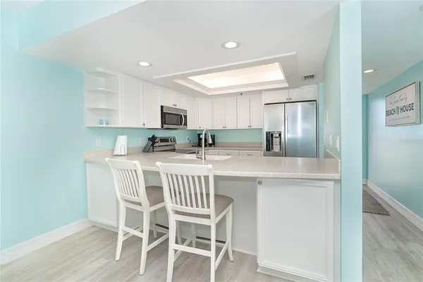 a kitchen with kitchen island granite countertop a dining table chairs refrigerator and cabinets