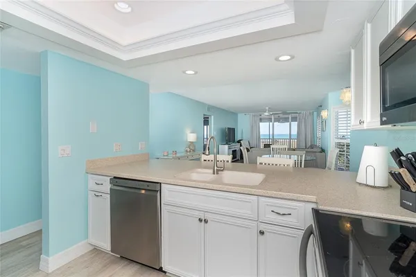 a kitchen with a sink dishwasher and white cabinets with wooden floor
