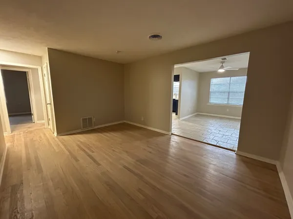 a view of an empty room with wooden floor and a window