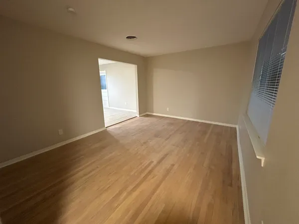 a view of an empty room with wooden floor and a window