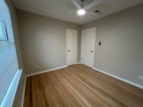an empty room with wooden floor and windows