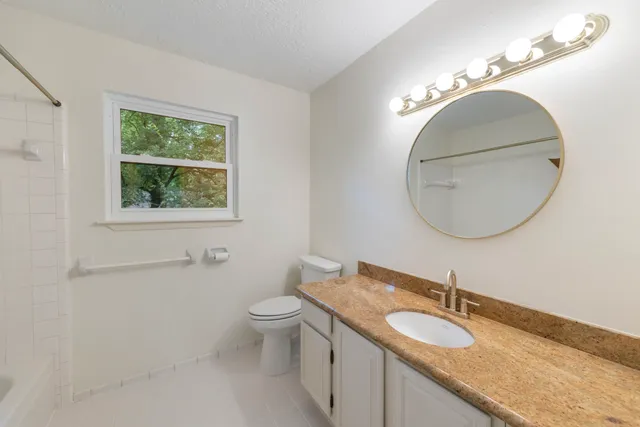 a bathroom with a granite countertop toilet a sink and a mirror