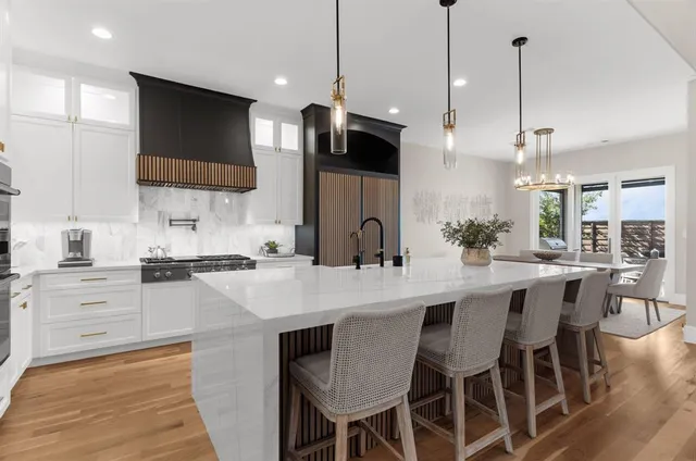 a kitchen with stainless steel appliances kitchen island granite countertop a sink a stove a refrigerator and island with wooden floor