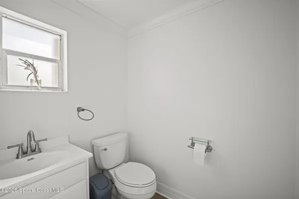 a bathroom with a toilet a sink a mirror and a window