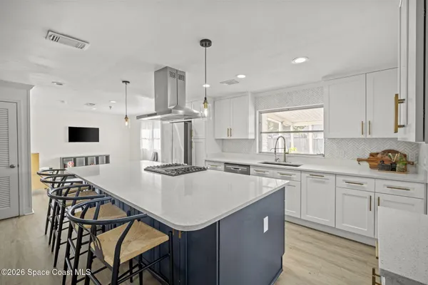 a kitchen with stainless steel appliances a sink a stove a refrigerator cabinets and dining table