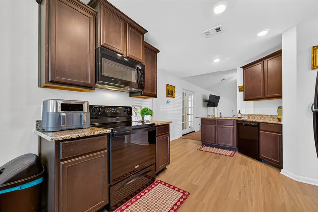 a kitchen with stainless steel appliances granite countertop wooden cabinets a stove top oven a sink and dishwasher