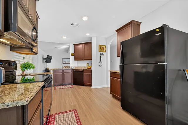 a kitchen with granite countertop a refrigerator stove and sink