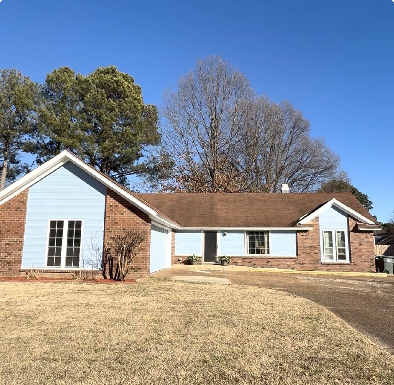 View of front facade featuring a front lawn, a garage, brick siding, and concrete driveway