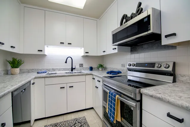 a kitchen with stainless steel appliances granite countertop a sink a stove and a microwave