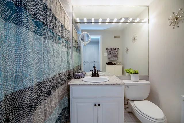 a bathroom with a granite countertop sink a toilet and a mirror