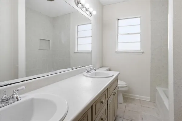 a bathroom with a granite countertop sink a toilet and a window