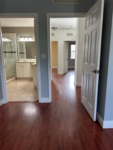 a view of a hallway with wooden floor and a bathroom