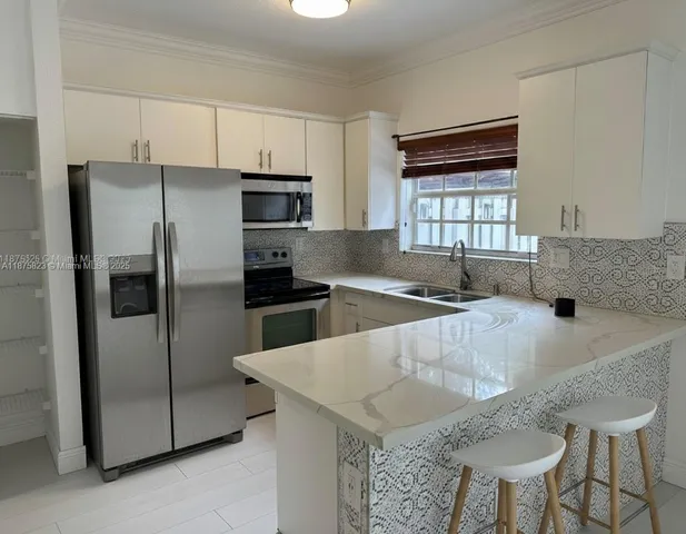 a kitchen with stainless steel appliances granite countertop a sink a microwave a refrigerator and white cabinets