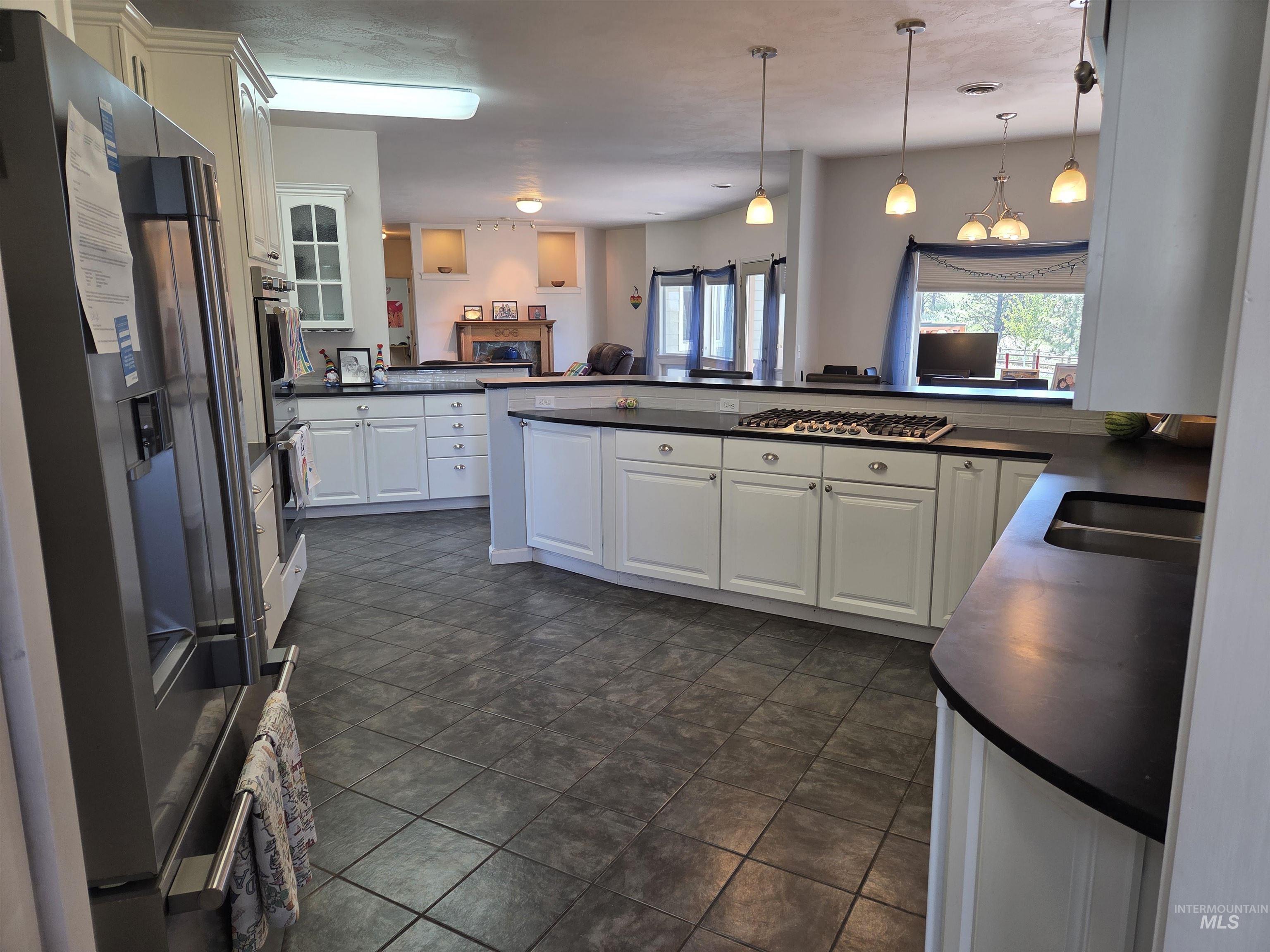 1085 Wallen Road Moscow, ID 83843 - Photo 9 of 50 Spacious kitchen featuring white cabinetry, dark countertops, a built-in gas range, tiled flooring, and pendant lighting