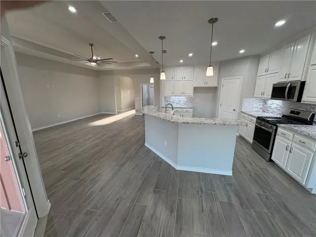 a large kitchen with stainless steel appliances granite countertop a lot of counter space and wooden floor