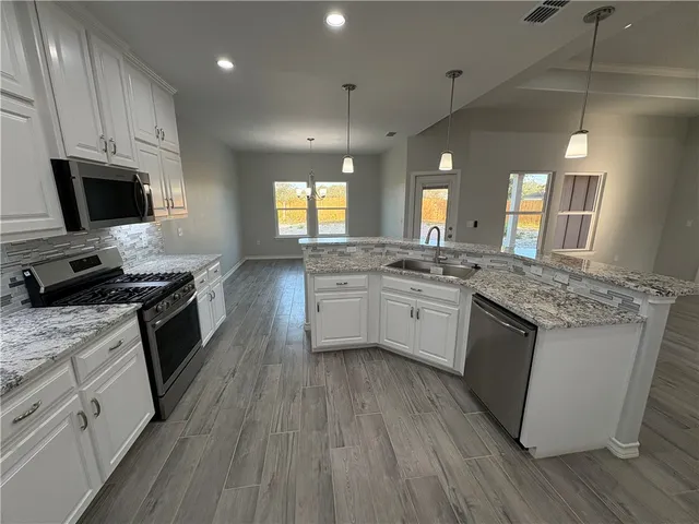 a kitchen with granite countertop a sink wooden floor and stainless steel appliances