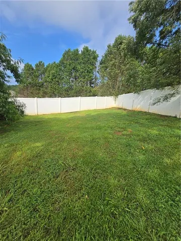 a view of yard with swimming pool and trees in the background