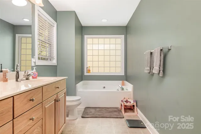 a spacious bathroom with a tub sink toilet and a window