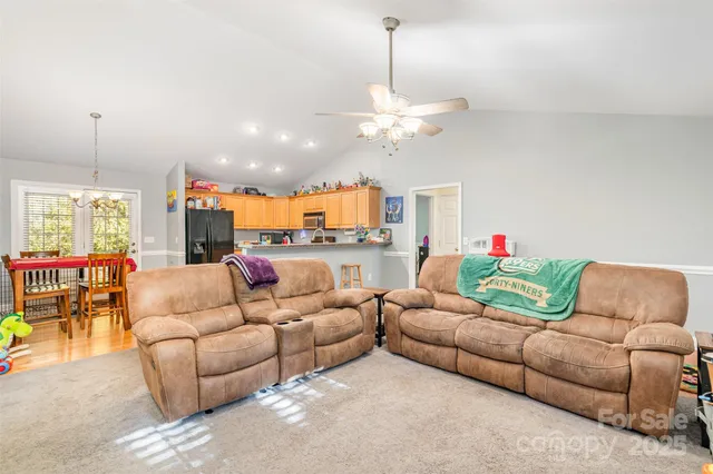 a living room with furniture kitchen view and a chandelier