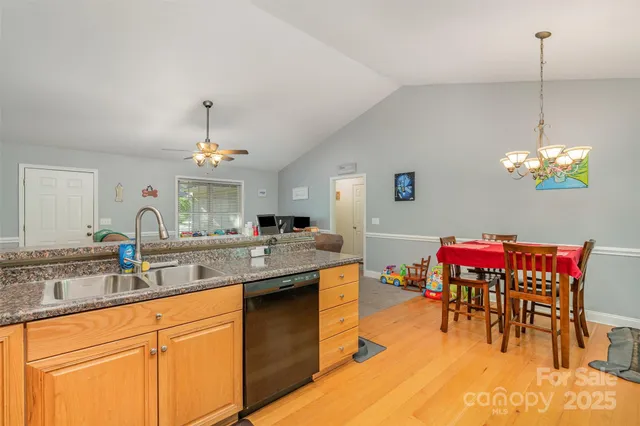 a kitchen with stainless steel appliances granite countertop a sink dishwasher and a dining table with chairs