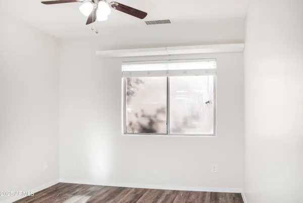 an empty room with a window and a ceiling fan