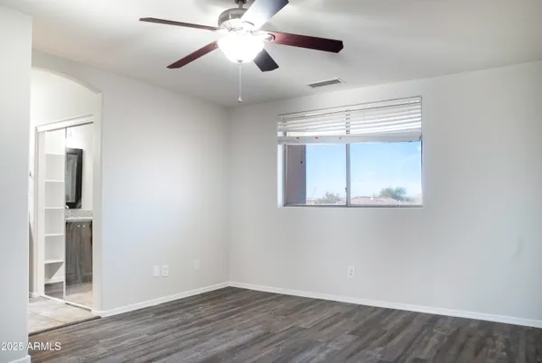 an empty room with wooden floor chandelier fan and windows