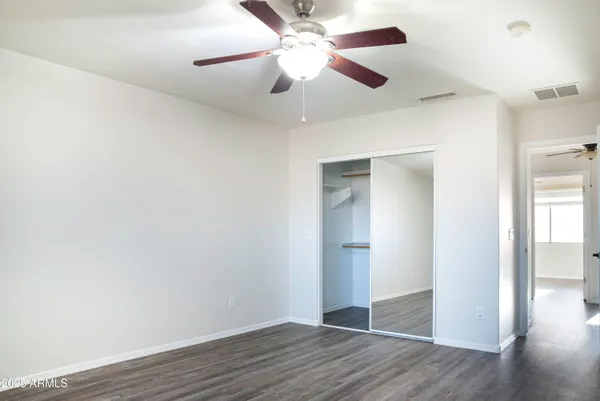 an empty room with wooden floor a ceiling fan and closet