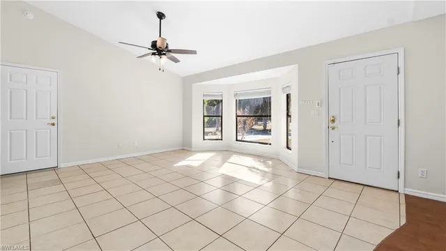 an empty room with chandelier fan and windows