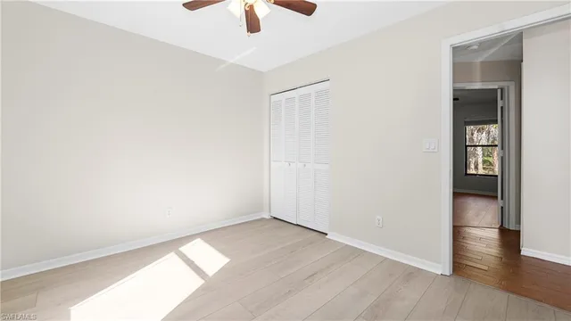 an empty room with wooden floor cabinet and windows