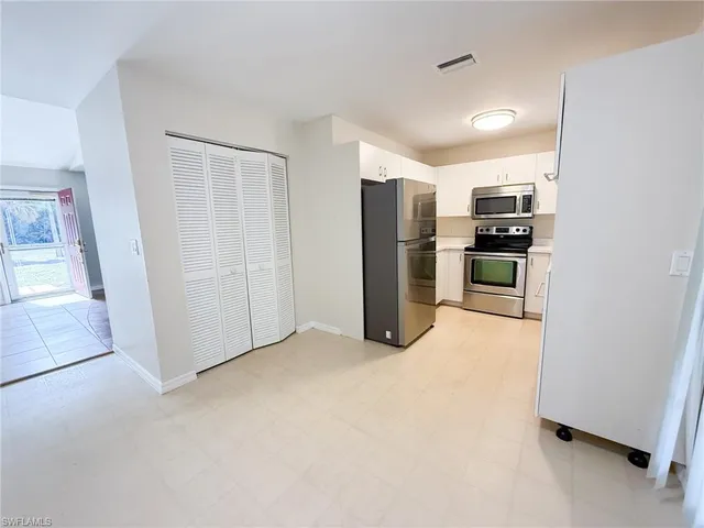 a view of a kitchen with refrigerator and white cabinets