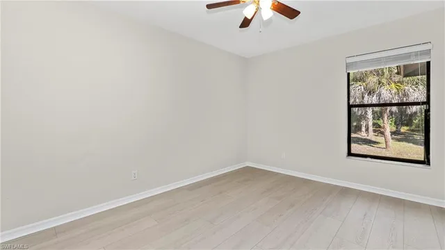 an empty room with a window and a ceiling fan