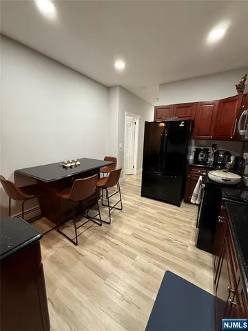 a kitchen with stainless steel appliances kitchen island granite countertop a stove top oven a sink dishwasher and cabinets with wooden floor